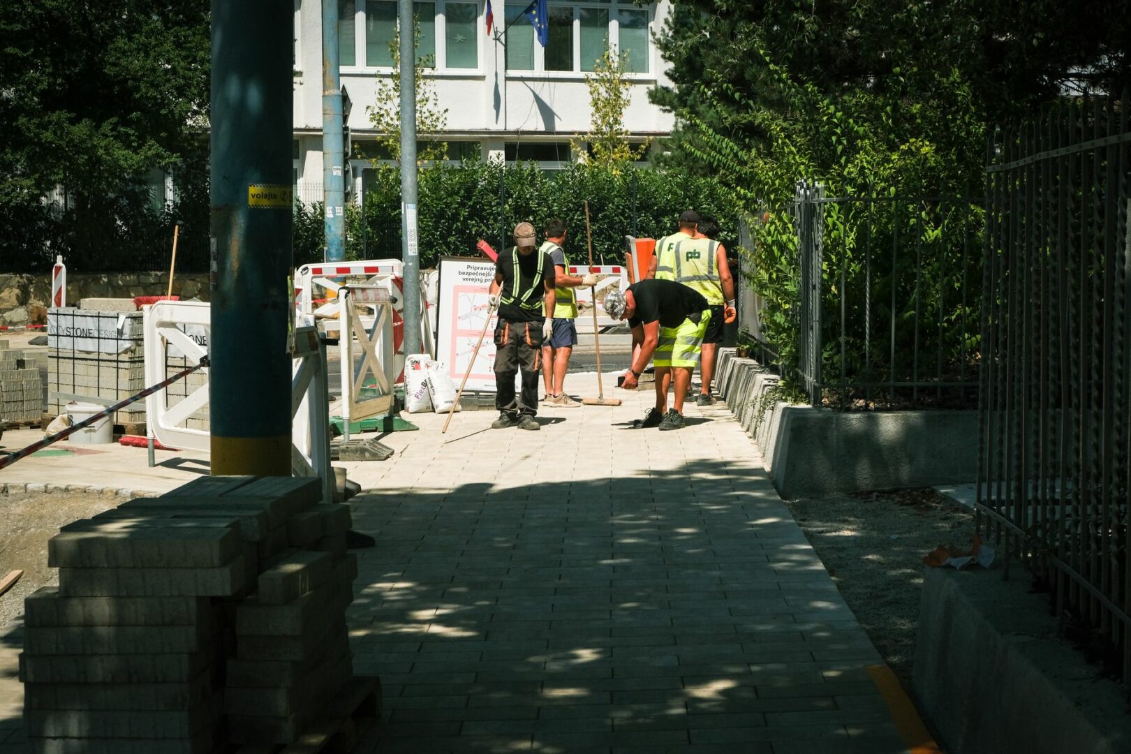 Team of construction workers paving a sidewalk outdoors on a sunny day in Bratislava.